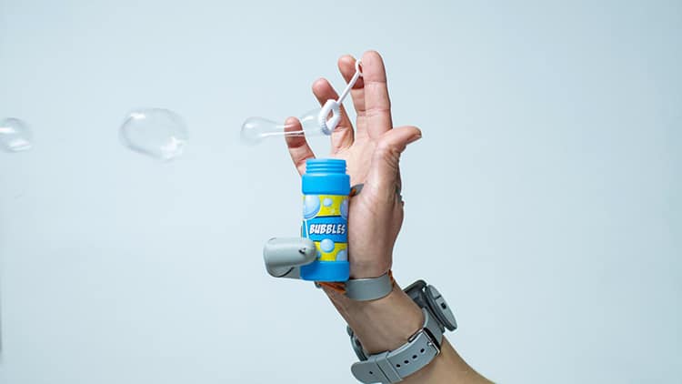 The 'Third Thumb' device being used to blow bubbles single-handedly.