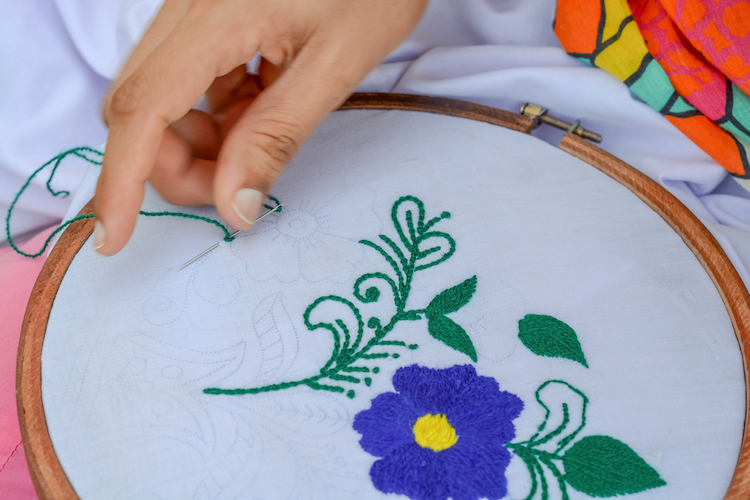 Person Stitching a Flower in an Embroidery Hoop