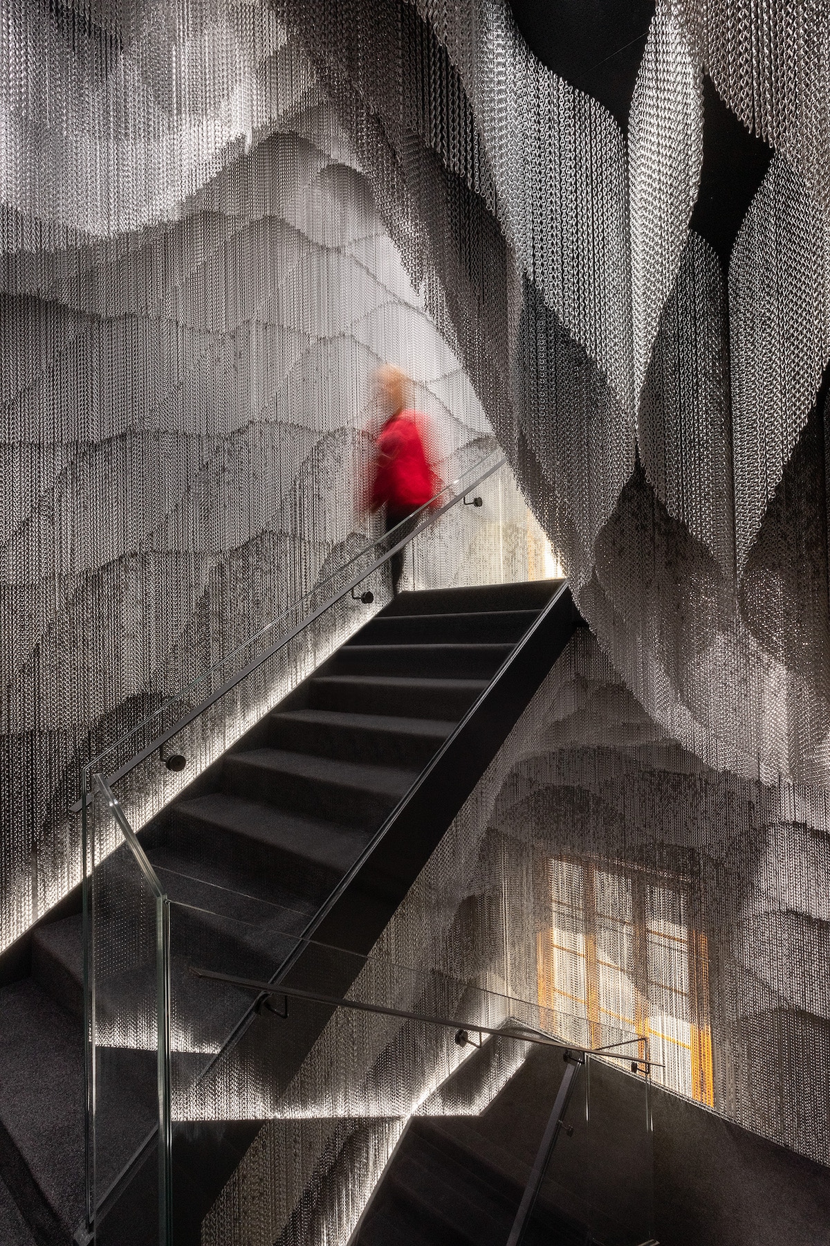 Person Passing Inside Kengo Kuma Aluminum Chain Staircase in Gaudí’s Casa Batlló, Captured by Jordi Anguera