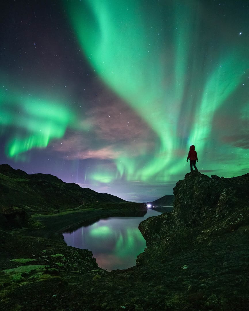 Person Standing on a Cliff Watching the Northern Lights