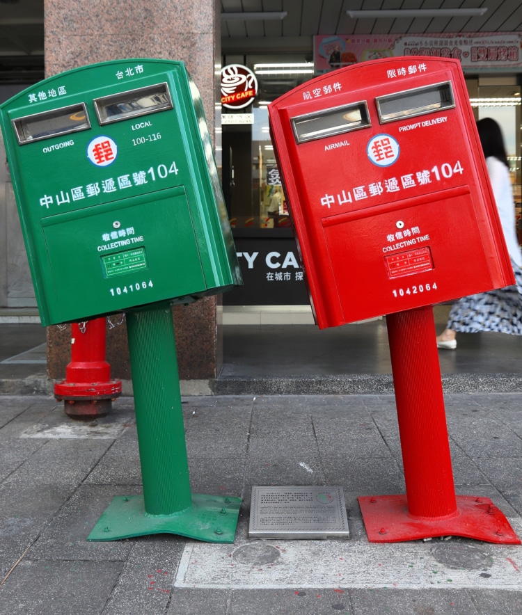 two taiwanese mailboxes bent by a hurricane, one green and one red