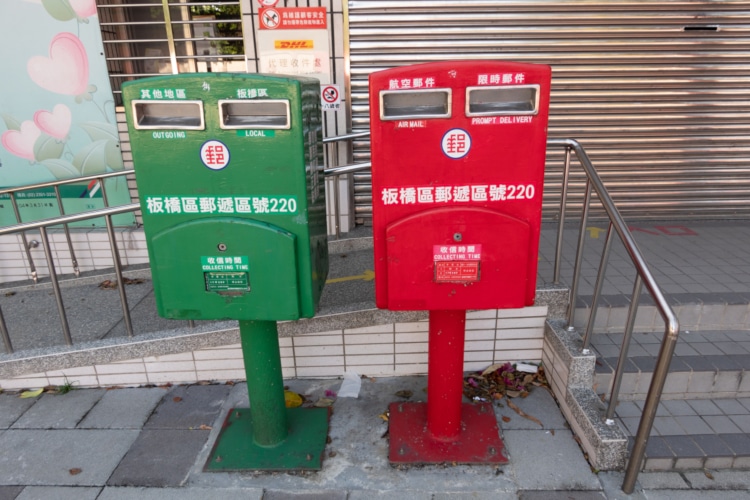 two taiwanese mailboxes, one green and one red