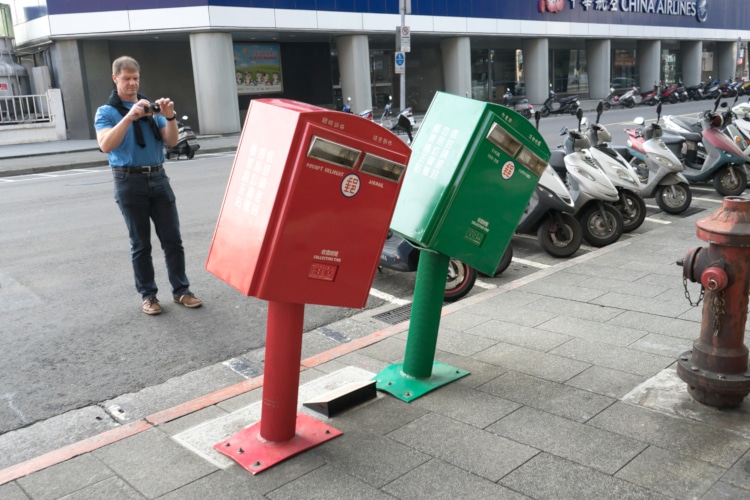 two taiwanese mailboxes bent by a hurricane, one green and one red