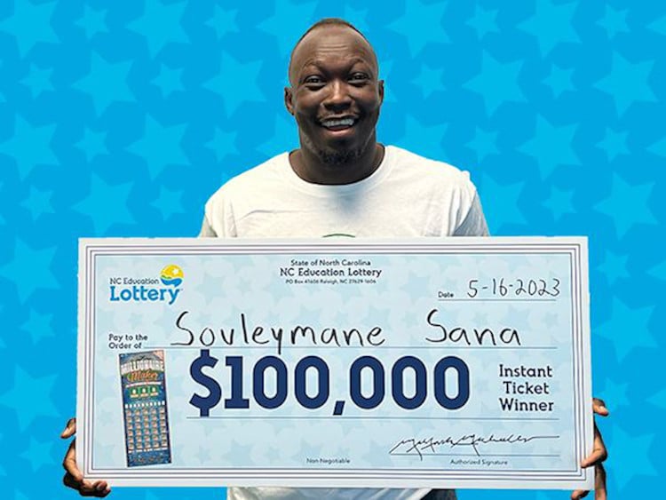 Souleymane Sana holds a novelty check for $100,000. He will use his wins to fund classrooms in Mali