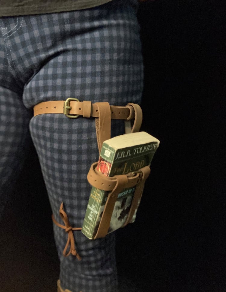 Leather thigh book holster being worn by person with blue pants