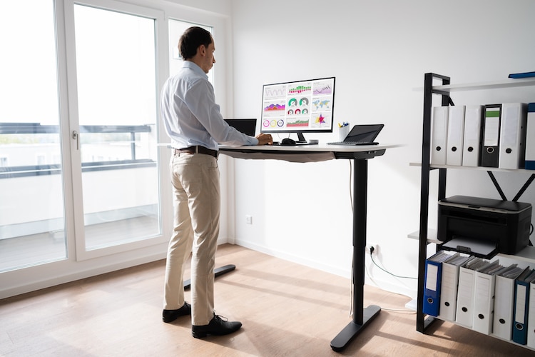 Man Working On Computer At Standing Desk In Home Office