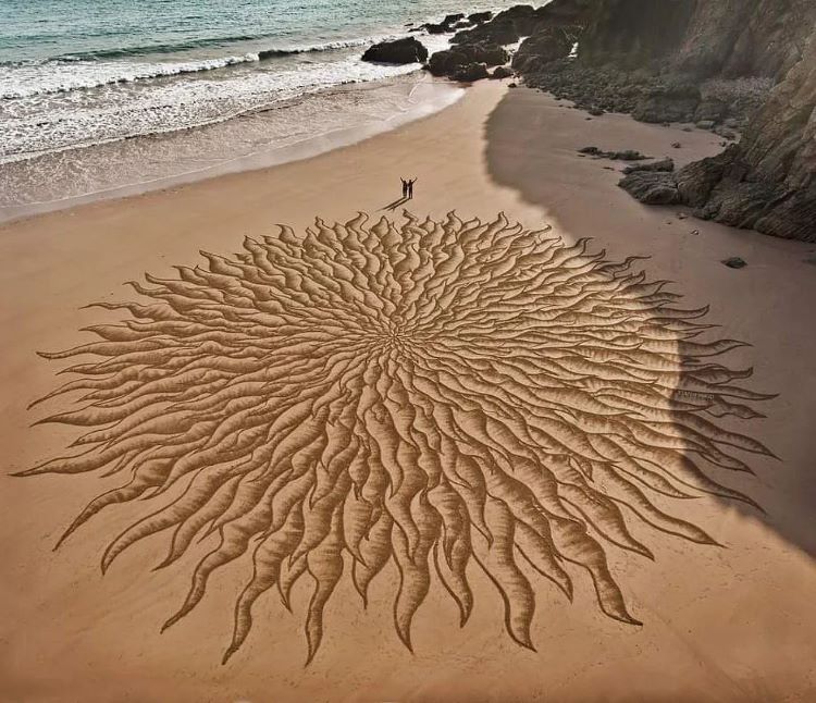 Jon Foreman And Friend Standing Next To Large Sun Design On Beach